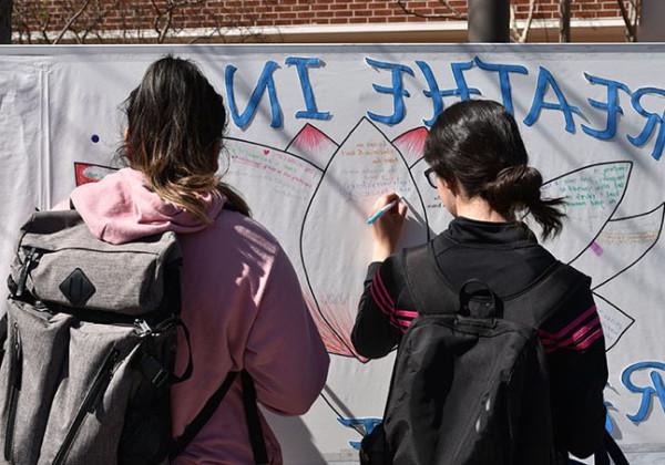 两个学生站在那里，在一块大黑板上写字.